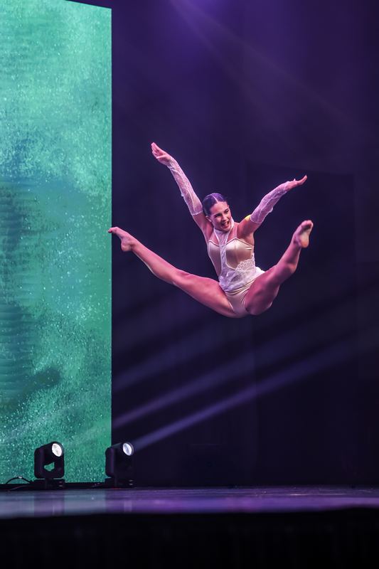 A dancer leaping across a dark stage
